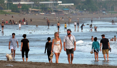 Tourists walk on Bali beach